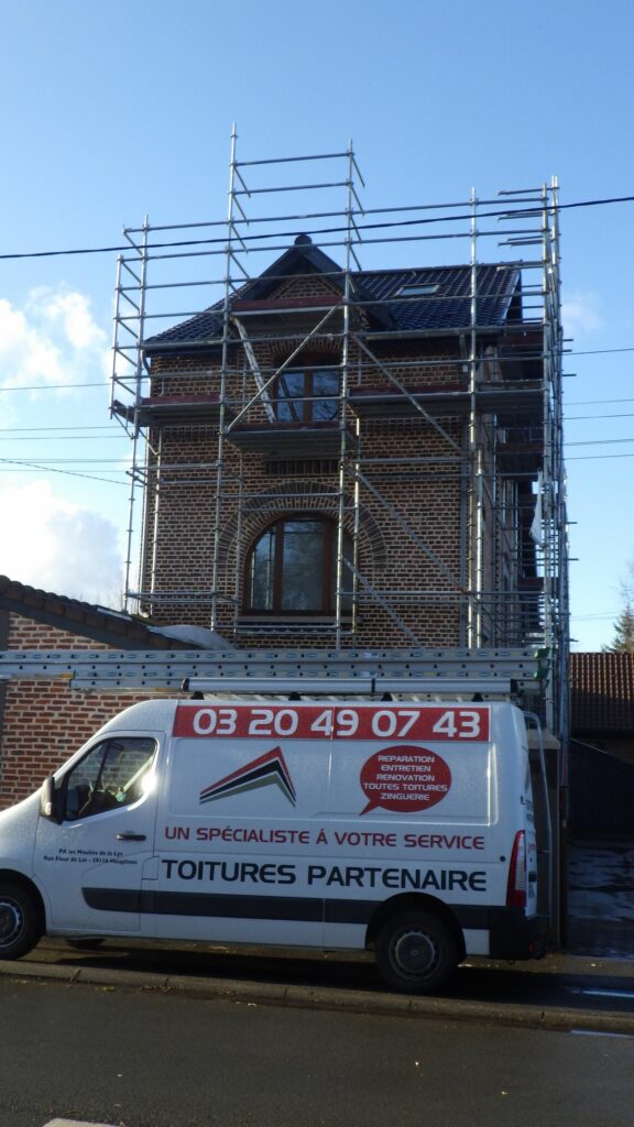 Maison en briques sous échafaudage et camion Toitures Partenaire pendant une réfection de toiture